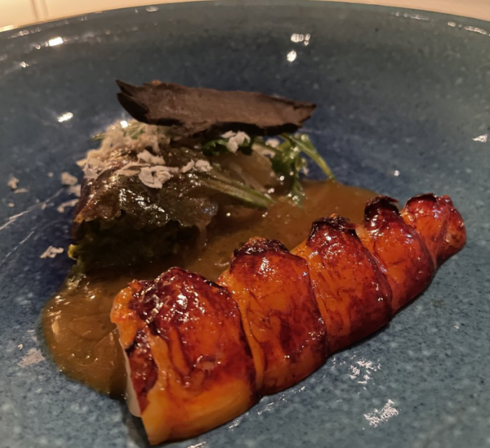 The bright red lobster tail on a blue ceramic plate